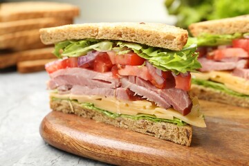 Delicious sandwich with ham, cheese and vegetables on grey textured table, closeup