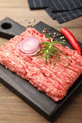 Raw minced meat with rosemary, thyme and spices on wooden table, closeup