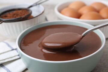 Raw chocolate dough in bowl and ingredients on grey table, closeup