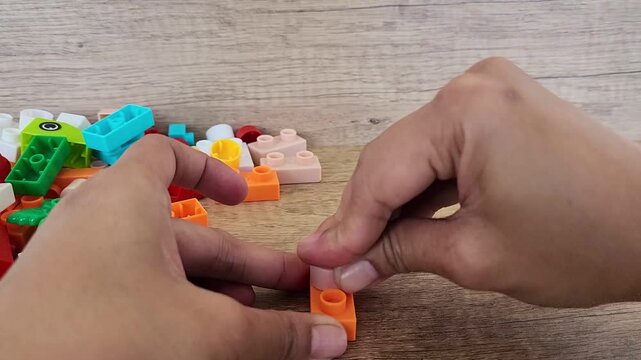 an asian woman is playing with lego forming the legs to form a giraffe with a brown background