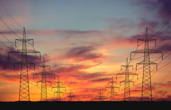 Silhouettes of power lines against the backdrop of sunset. The concept of energy transportation, technology, and infrastructure for power plants. Industry and the population depend on electricity.