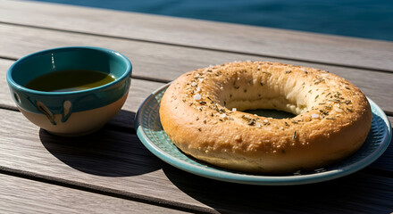 Close-up of a appetizing bagel and olive oil in a bowl on a wooden table, outside