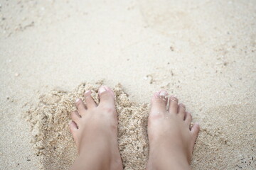 Bare feet touching sandy beach, symbolizing relaxation, calmness, and peaceful vacation moments.