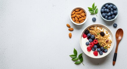 Healthy breakfast bowl with yogurt, granola, fresh berries, and almonds, with a wooden spoon