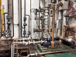 Complex industrial piping system with pumps and valves in a power plant or chemical factory. The heavy-duty machinery and complex utility infrastructure highlight essential manufacturing, plumbing,