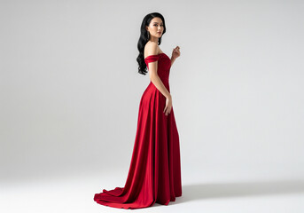 A woman in a flowing red gown poses elegantly, looking over her shoulder.