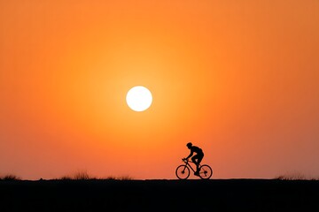Obraz premium Silhouette of Cyclist Riding Against Vibrant Sunset Sky and Dazzling Sun