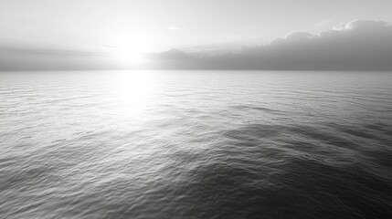 Vast monochrome ocean at sunrise, sun reflecting on waves, distant clouds on horizon