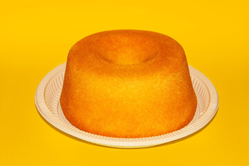 CORNMEAL CAKE ON A PLASTIC PLATE ISOLATED ON A YELLOW BACKGROUND