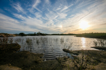The general plan. A picturesque pond surrounded by flowers against a sunset background. Khasansky district of Primorsky Krai.