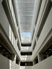 Obraz premium Modern building interior with atrium and skylight, looking up at geometric patterns and natural light