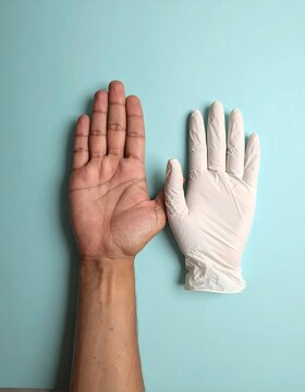 One bare hand and a gloved hand side-by-side on a turquoise surface