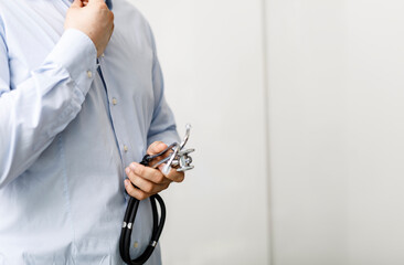 Close-up of a doctor in a blue shirt holding a stethoscope, healthcare, medicine, and professional...