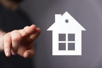 Hand pointing towards a house symbol, real estate, mortgage, home ownership, property investment and dream of owning a home concept. Financial f