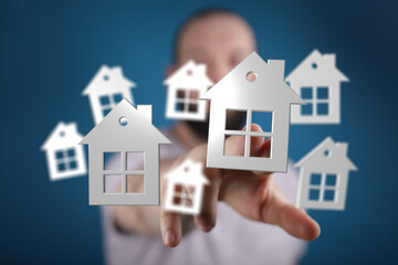 Conceptual image of a man's hand selecting a house from a group. Representing property, choice,...