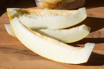slices of sliced melon are placed on a wooden surface in sunlight