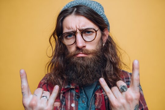 A young hipster with long hair and glasses displays a negative gesture with crossed fingers