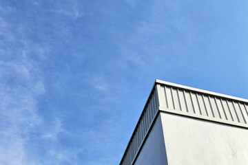 Modern building with standing seam metal cladding under a clear blue sky.