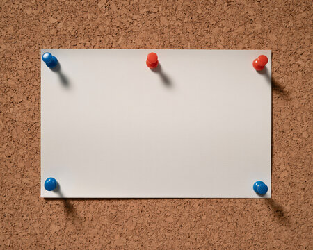 Blank white paper on corkboard, pinned with colorful push pins, perfect for announcements, memos, or creative projects, ideal for office or home use