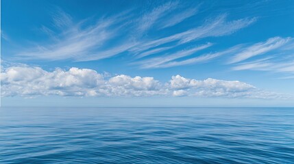 Fototapeta premium Sparkling Sea Surface Under a Blue Sky with White Clouds—An Endless Expanse of Ocean Glistening in the Sunlight, Creating a Serene, Breathtaking Scene Perfect for Wallpapers, Travel Photos