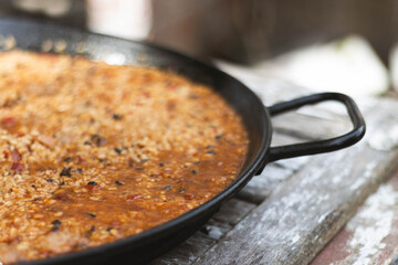 Homemade paella served in a rustic pan on wooden table traditional Spanish cuisine