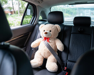 Adorable teddy bear buckled up safely in the back seat of a car ready for a fun trip, promoting child safety and responsible travel habits