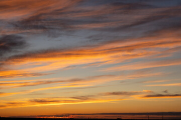 Fototapeta premium A beautiful sunrise with warm orange and yellow hues illuminating soft clouds across the sky. 