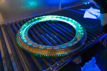 Non-destructive testing of an aerospace engine component using the fluorescent penetrant inspection method to reveal surface discontinuities under UV light inspection