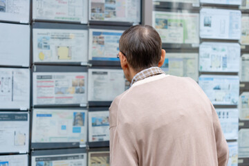 不動産広告を見るシニア男性