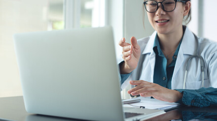 Asian female doctor using laptop computer online video call, telemedicine to patient, prescribe medicine. Tele medical, health care service. Doctor online meeting with medical team via laptop