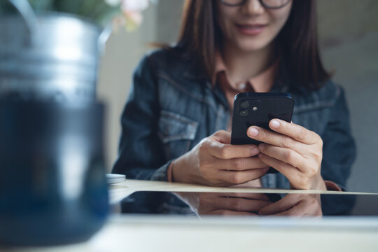 Close up, young asian woman using mobile phone for online shopping, digital banking and social networking via mobile app at coffee shop, surfing the internet, online messaging, people lifestyle