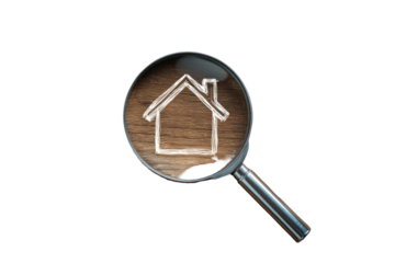 Magnifying glass focuses on a house silhouette drawn on a wooden surface, all against black