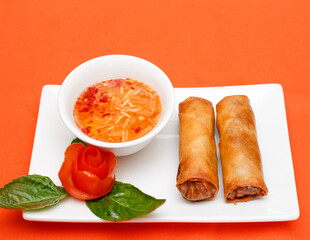 Fried Spring Rolls Served with Dipping Sauce and Tomato Garnish