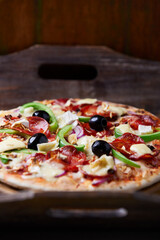 Pizza with salami, mozzarella cheese and jalapeno pepper. Wooden background. Soft focus.	