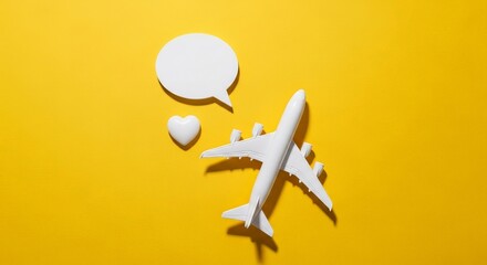A white toy airplane, heart and speech bubble are thoughtfully arranged on bright yellow background.