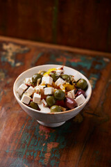 Green and kalamata olives and feta cheese on rustic wooden background. Soft focus.