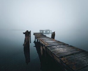 Foggy dock stretches into still lake