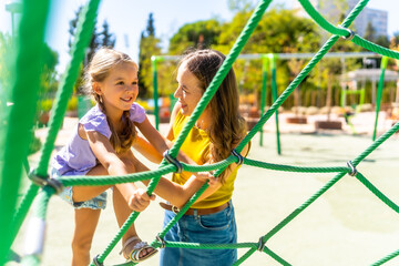 Mother and daughter playing and climbing on playground rope net