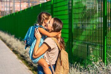 Mother hugging daughter going to school