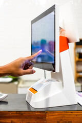 Selective focus to customer's hand is touching a touch screen to order food and pay electronically.