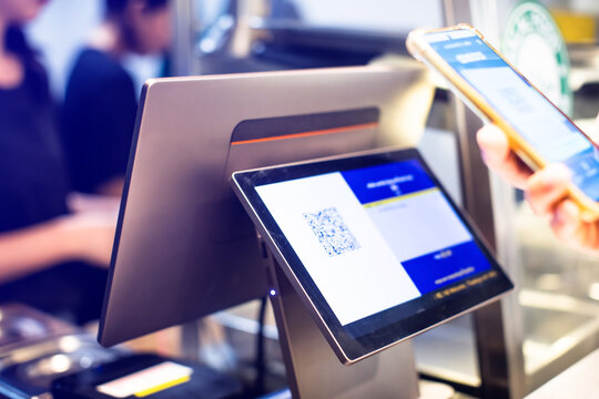 Selective focus to POS Machine with blurry customer scan QR code to payment and receipt at cash register machine in restaurant.