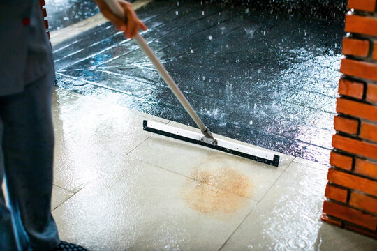 Selective focus to worker using wiper or squeegee to clean floor surface. Staff cleaning floor with wiper. The concept of cleaning service.