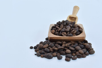 Coffee beans placed on a wooden container and wooden spoon on a white background