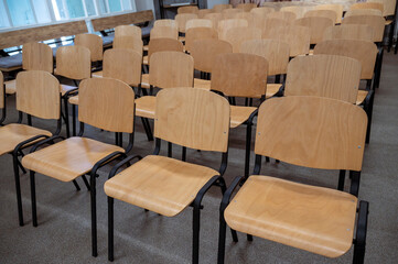 Rows of empty wooden chairs in a meeting room