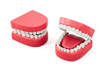 Two cartoon-style red plastic dentures with white teeth and one showing a tongue, isolated on white background. Dental humor and anatomy concept. 3D Rendering