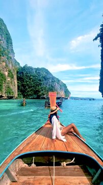 Asian woman journey through Thailands breathtaking scenery aboard a longtail boat at Koh Phi Phi. Crystal clear waters and towering cliffs create a tranquil escape. woman onvacation in Thailand