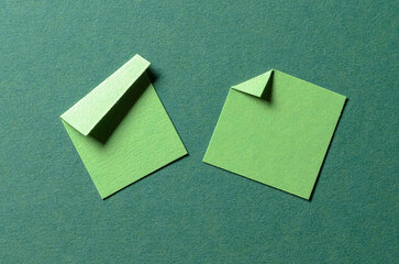 Pieces of blank green paper notes or sheets with folded edge dog-ear earmark and copy space for text, top view flat lay