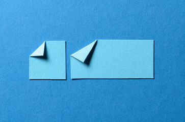 Pieces of blank paper notes or sheets with folded edge dog-ear earmark and copy space for text on blue background, top view flat lay