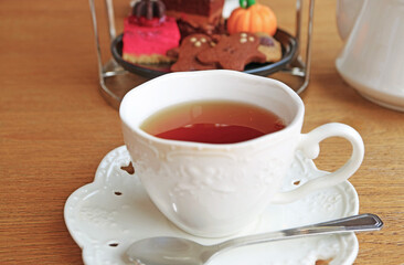 Cup of Hot Tea with Blurry Halloween Theme Tea Pastries the Backdrop