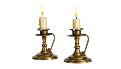 Two lit candles in brass candlestick holders, isolated on transparent background